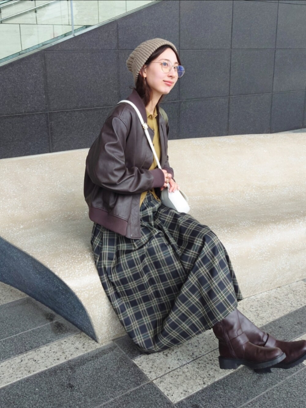 グリーン系のスカート、ホワイト系のショルダーバッグ、ブラウン系のノーカラージャケットを着用したレディースの秋コーディネートの2枚目の写真