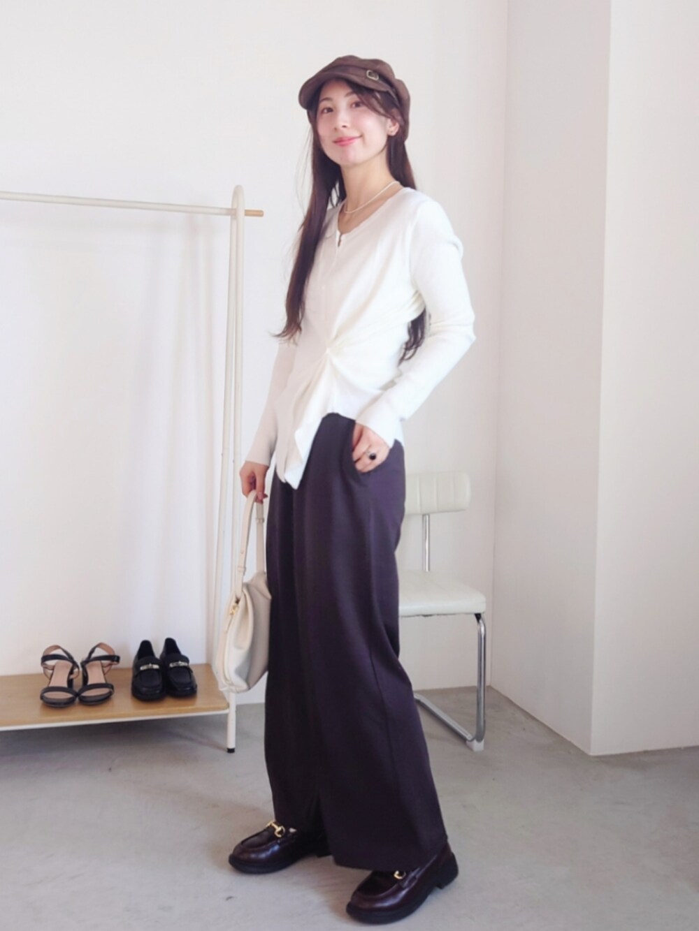 ホワイト系のショルダーバッグ、ブラウン系のパンツ、ブラウン系のキャスケットを着用したレディースの春コーディネートの2枚目の写真