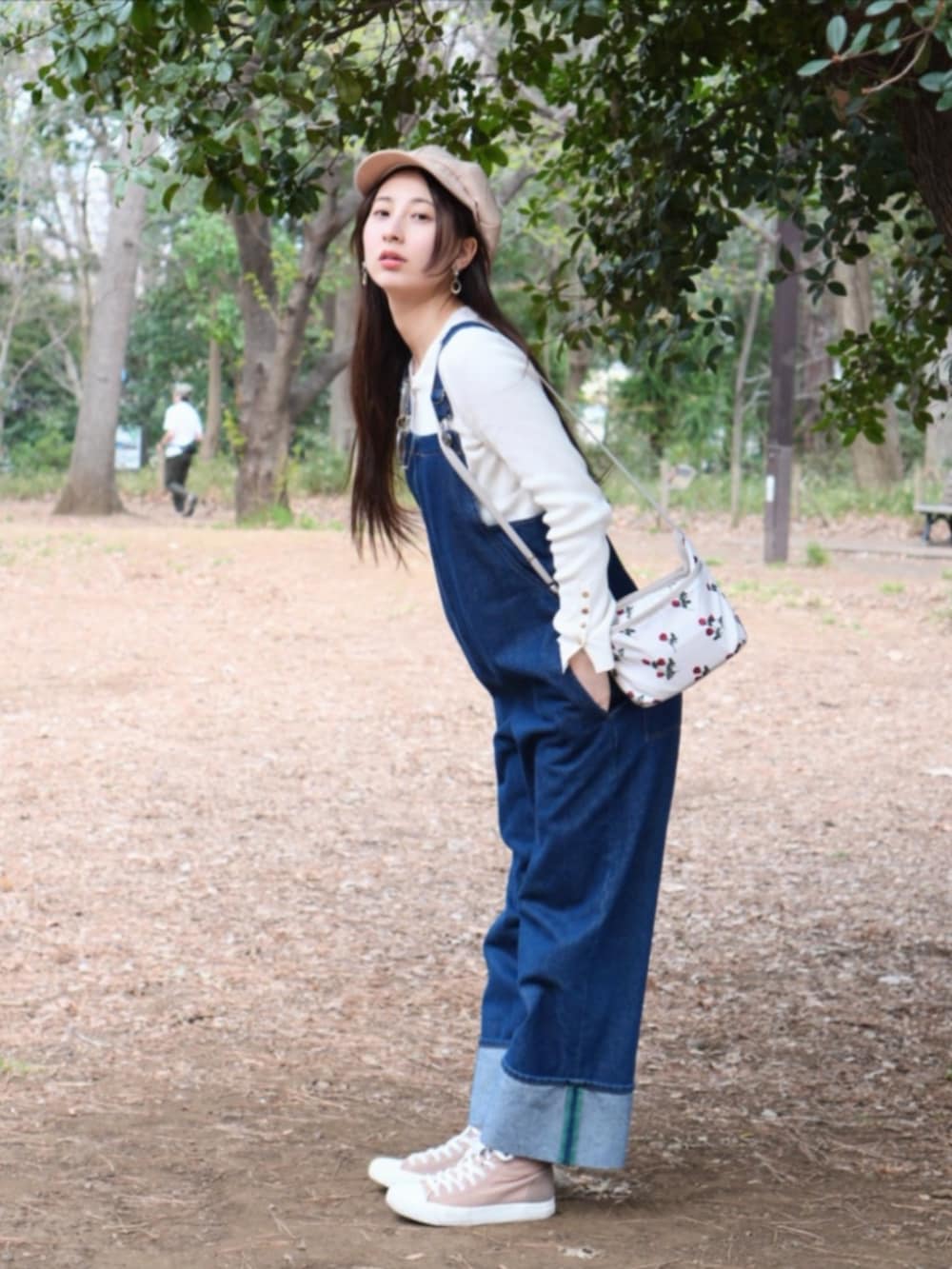 ブラウン系のスニーカー、ブルー系のサロペット/オーバーオール、ホワイト系のショルダーバッグを着用したレディースの春コーディネートの3枚目の写真