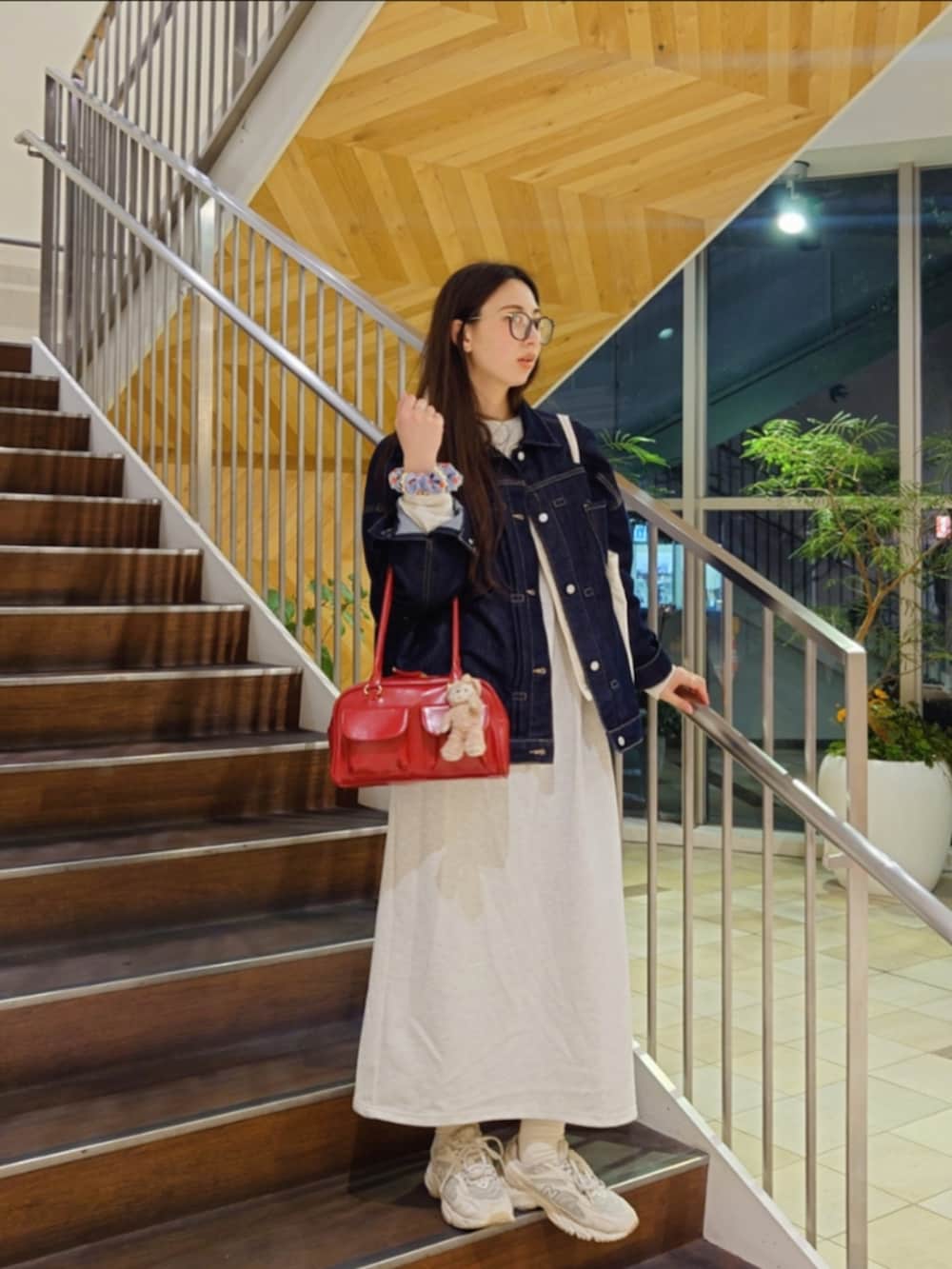 ブルー系のデニムジャケット、レッド系のトートバッグ、ホワイト系のスニーカーを着用したレディースの春コーディネートの2枚目の写真