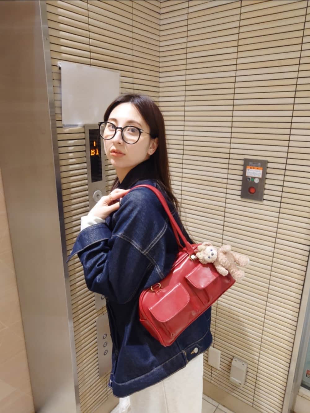 ブルー系のデニムジャケット、レッド系のトートバッグ、ホワイト系のスニーカーを着用したレディースの春コーディネートの3枚目の写真