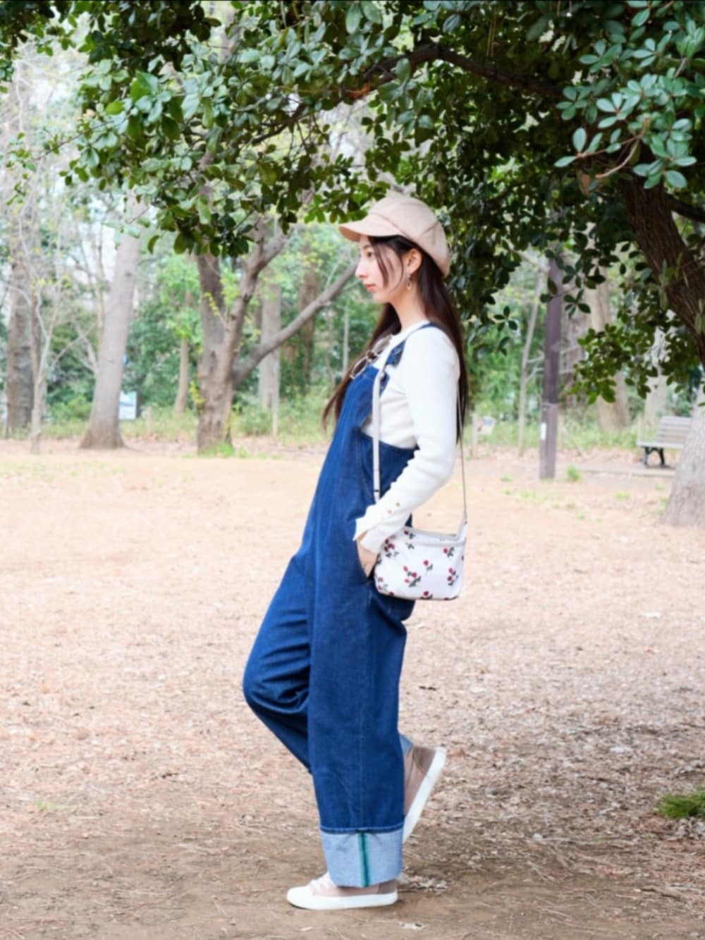 ブラウン系のスニーカー、ブルー系のサロペット/オーバーオール、ホワイト系のショルダーバッグを着用したレディースの春コーディネートの2枚目の写真