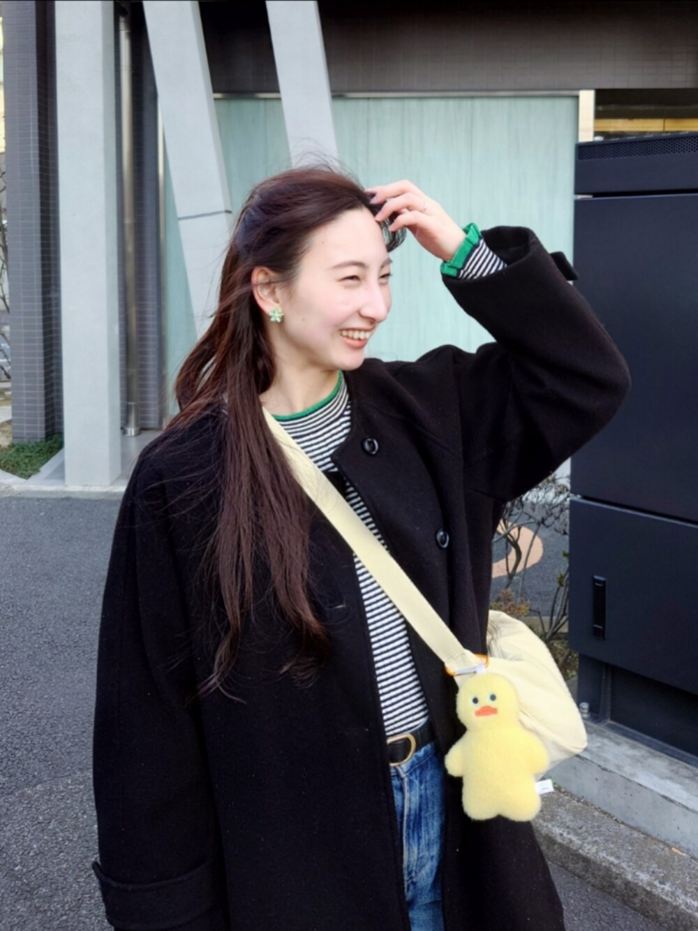 ブルー系のデニムパンツ、ブルー系のニット/セーター、ブラック系のノーカラーコートを着用したレディースの春コーディネートの2枚目の写真