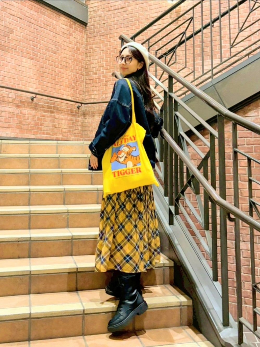 イエロー系のスカート、ホワイト系のショルダーバッグ、ブルー系のデニムジャケットを着用したレディースの秋コーディネートの2枚目の写真