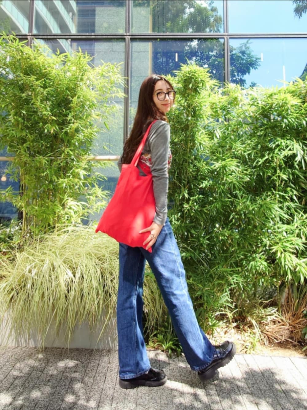 グレー系のTシャツ/カットソー、ブルー系のデニムパンツ、レッド系のトートバッグを着用したレディースの秋コーディネートの2枚目の写真