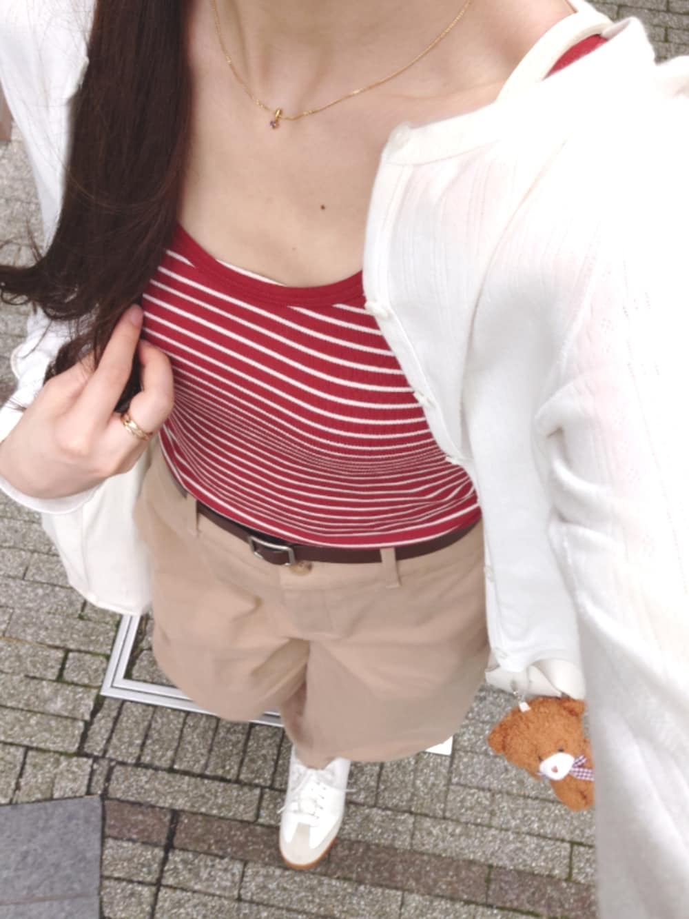 ベージュ系のチノパンツ、ホワイト系のカーディガン/ボレロ、レッド系のタンクトップを着用したレディースの夏コーディネートの2枚目の写真