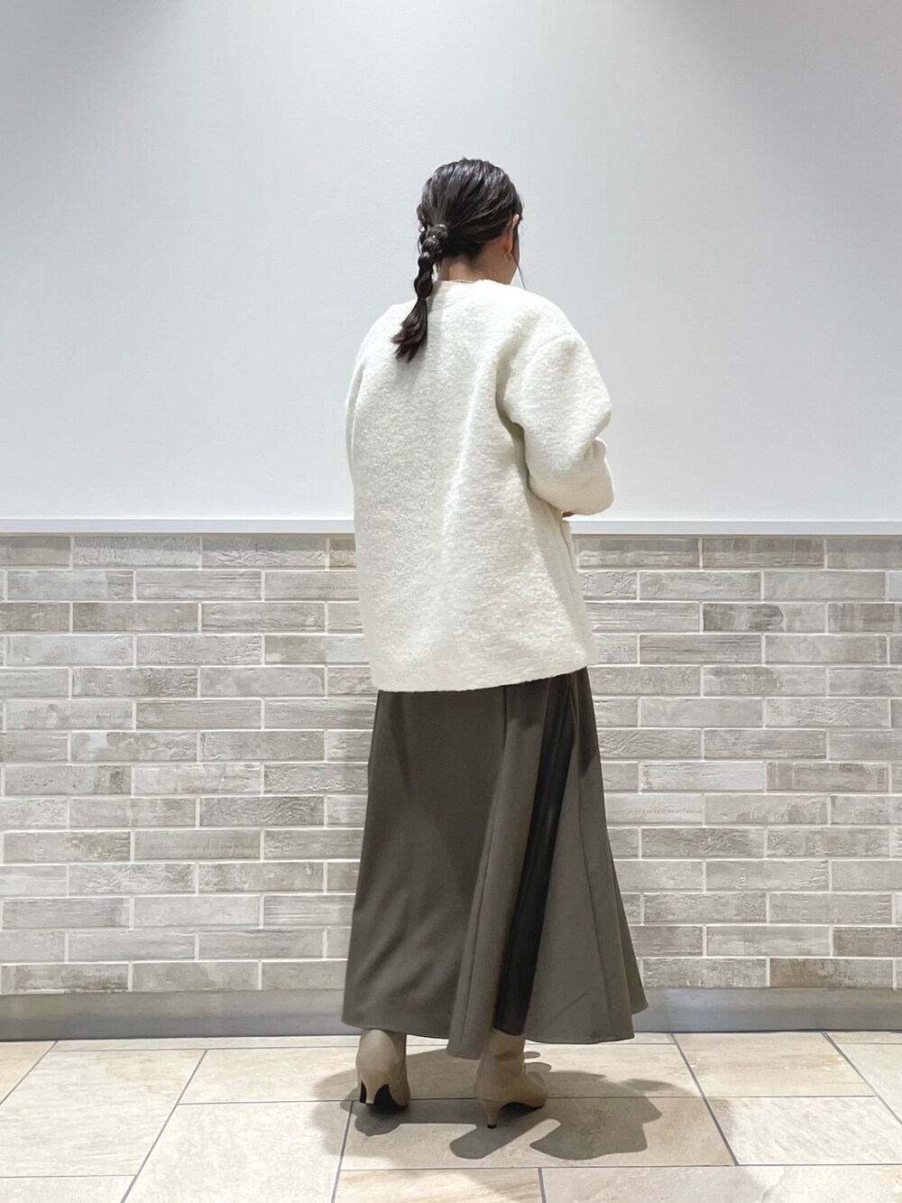 ホワイト系のその他アウター、グリーン系のスカート、ブラウン系のブーツを着用したレディースの冬コーディネートの3枚目の写真