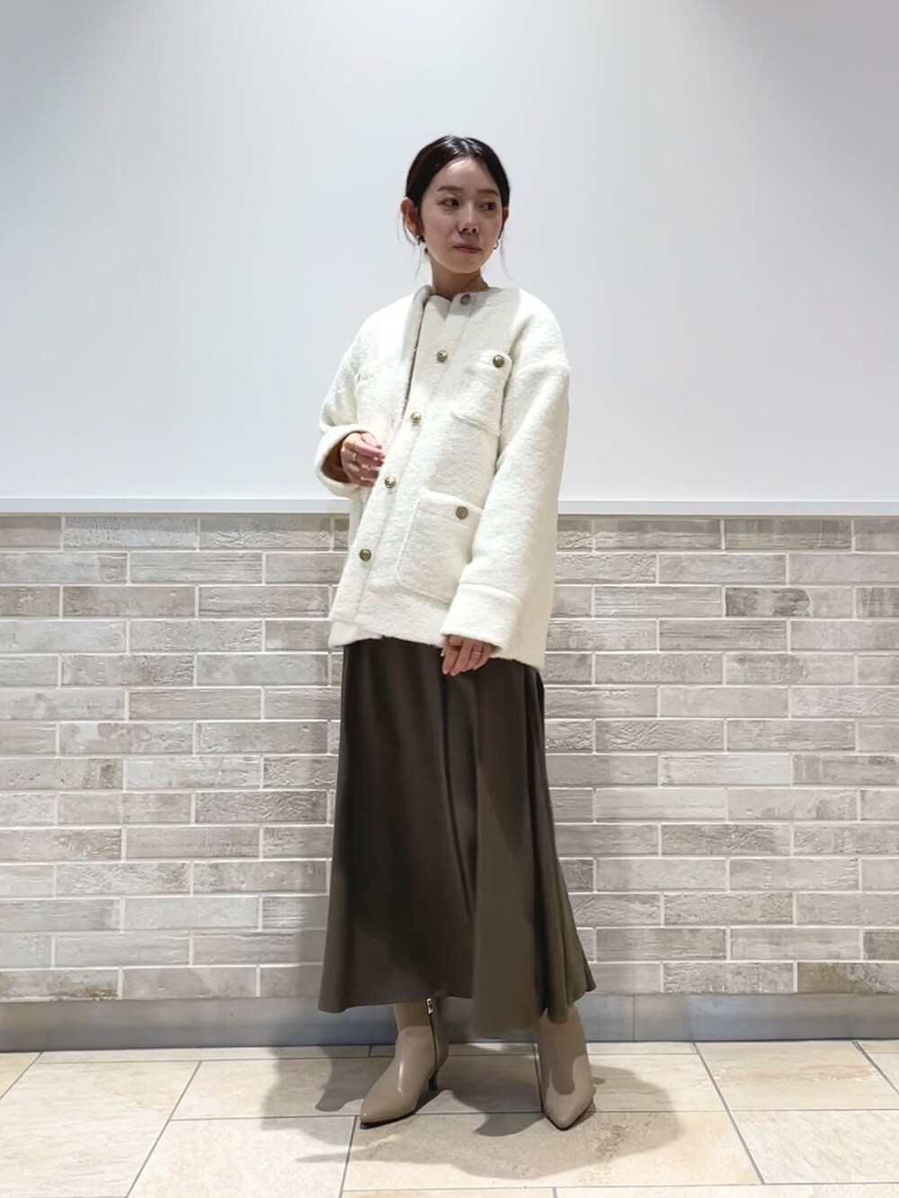 ホワイト系のその他アウター、グリーン系のスカート、ブラウン系のブーツを着用したレディースの冬コーディネートの2枚目の写真
