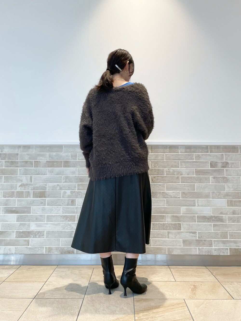 ブルー系のニット/セーター、ブラック系のスカート、ブラック系のブーツを着用したレディースの秋コーディネートの3枚目の写真