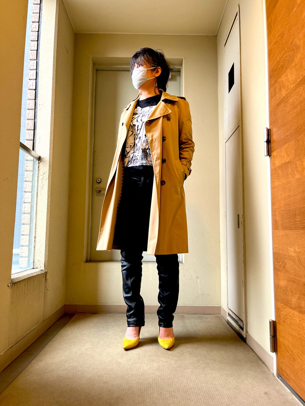 イエロー系のパンプス、ブラック系のTシャツ/カットソー、ベージュ系のトレンチコートを着用したレディースの春コーディネートの2枚目の写真