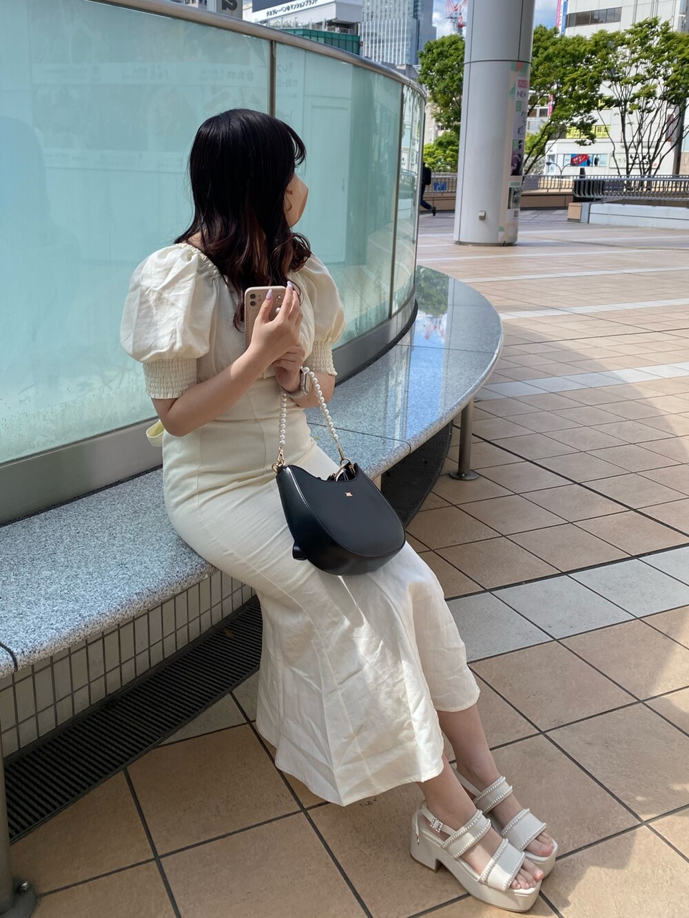 ホワイト系のワンピース、ホワイト系のサンダル、ブラック系のショルダーバッグを着用したレディースの春コーディネートの2枚目の写真