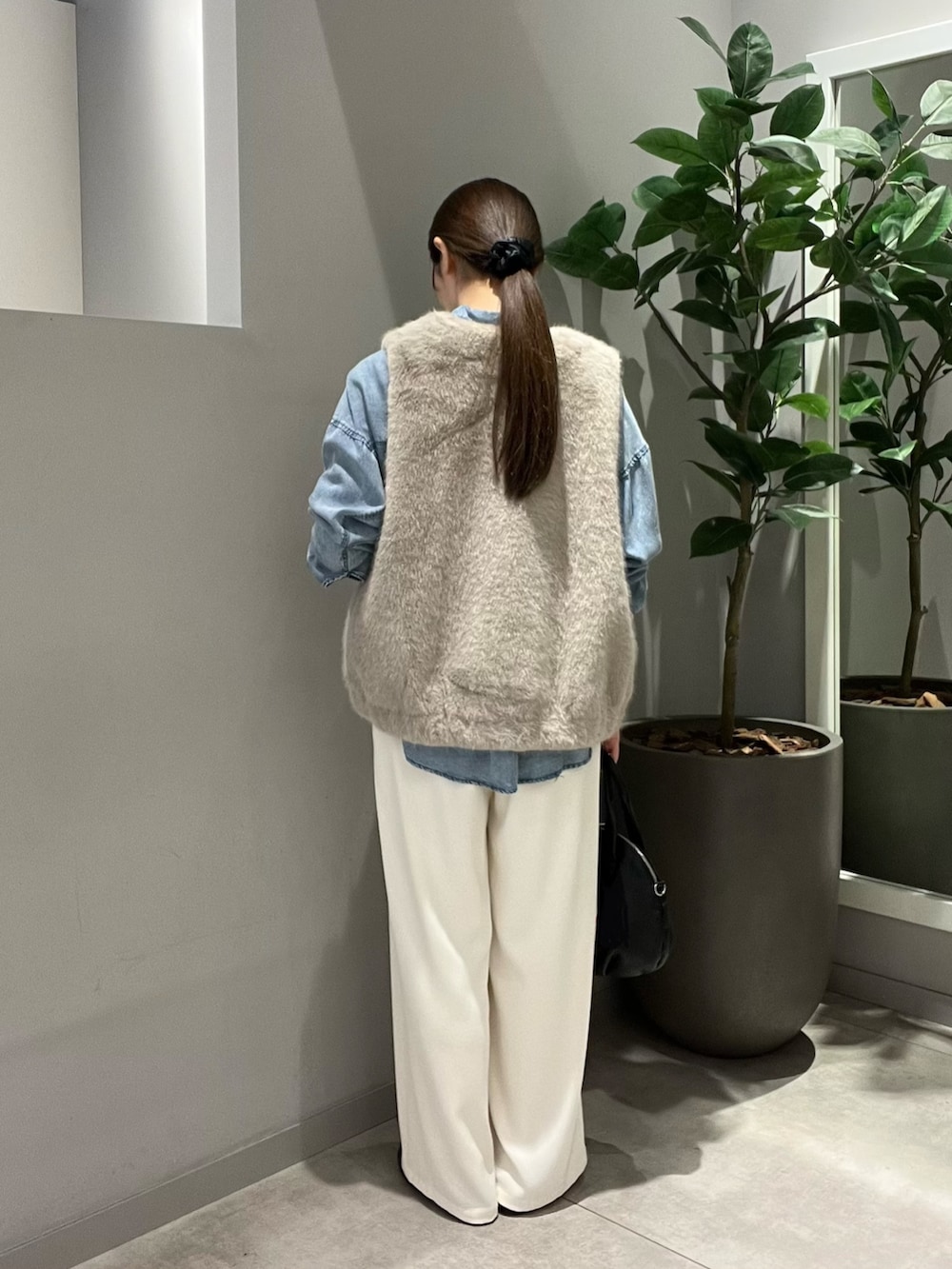 ブルー系のシャツ/ブラウス、ベージュ系のベスト、ブラック系のトートバッグを着用したレディースの秋コーディネートの3枚目の写真