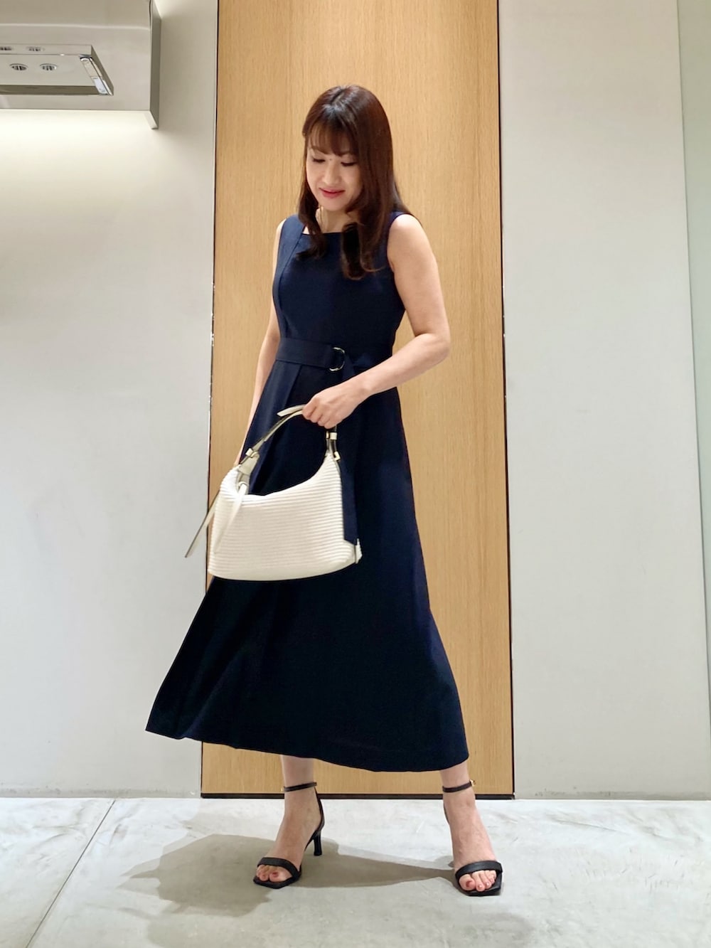 ブルー系のワンピース、ホワイト系のハンドバッグ、ホワイト系のイヤリングを着用したレディースの夏コーディネートの2枚目の写真