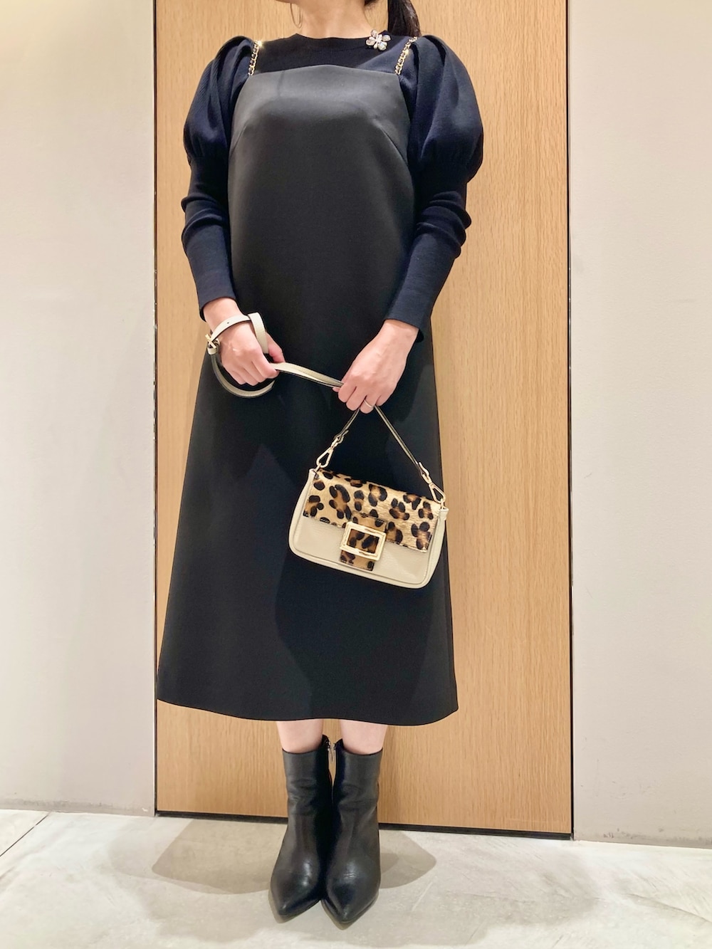 ブラック系のニット/セーター、ブラック系のワンピース、ホワイト系のバックパック/リュックを着用したレディースの秋コーディネートの2枚目の写真