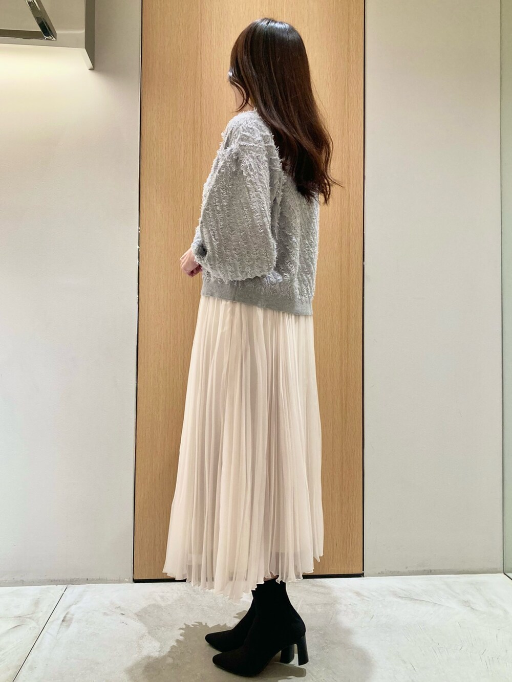 グレー系のニット/セーター、ホワイト系のスカート、シルバー系のネックレスを着用したレディースの秋コーディネートの5枚目の写真