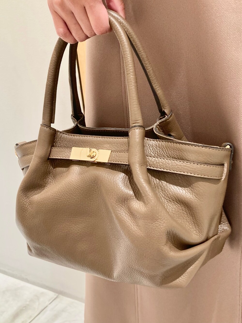 ベージュ系のシャツ/ブラウス、ベージュ系のスカート、ベージュ系のハンドバッグを着用したレディースの秋コーディネートの9枚目の写真