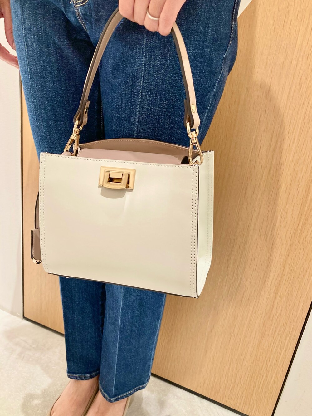 ホワイト系のシャツ/ブラウス、ホワイト系のハンドバッグ、ブルー系のデニムパンツを着用したレディースの秋コーディネートの9枚目の写真