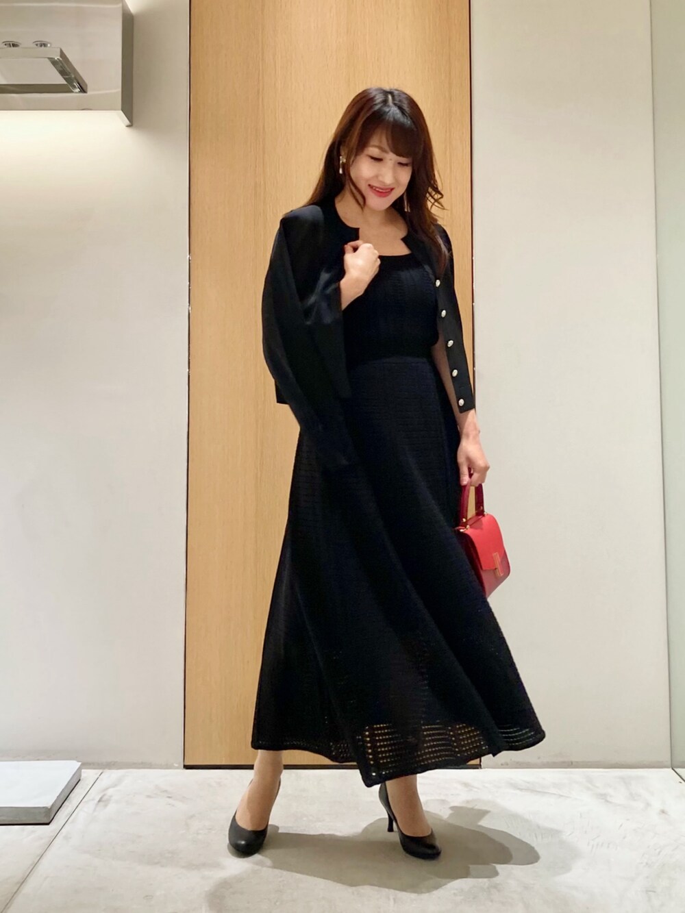 ブラック系のカーディガン/ボレロ、ブラック系のワンピース、レッド系のハンドバッグを着用したレディースの秋コーディネートの3枚目の写真