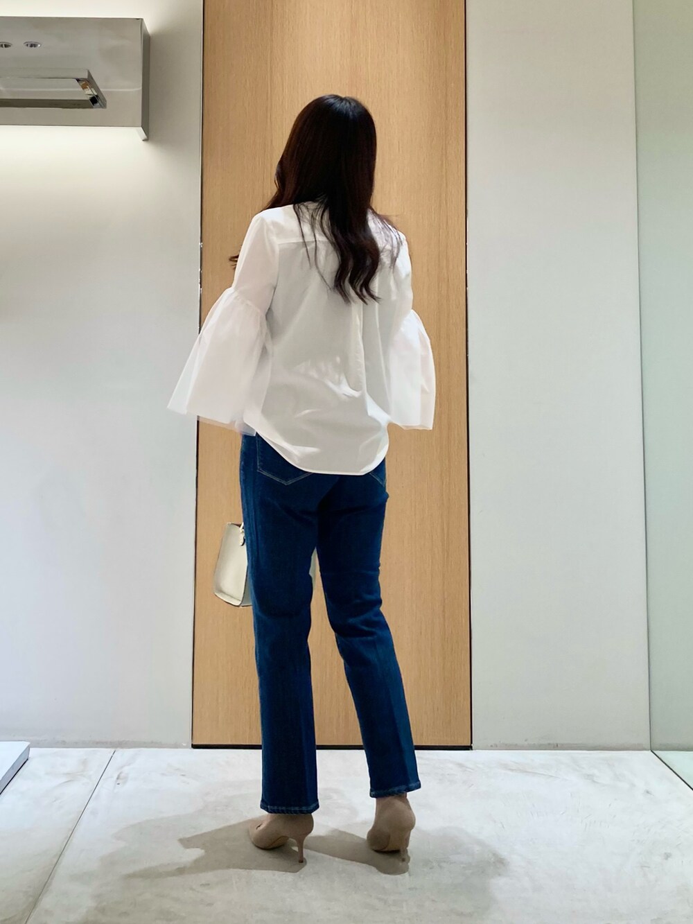 ホワイト系のシャツ/ブラウス、ホワイト系のハンドバッグ、ブルー系のデニムパンツを着用したレディースの秋コーディネートの4枚目の写真