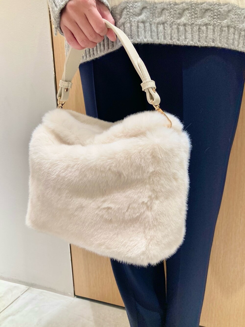 グレー系のニット/セーター、ブルー系のその他パンツ、ホワイト系のハンドバッグを着用したレディースの冬コーディネートの5枚目の写真