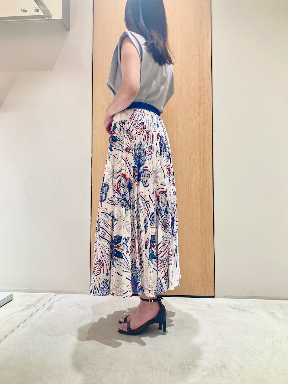 グレー系のニット/セーター、ブルー系のスカート、ホワイト系のネックレスを着用したレディースの夏コーディネートの3枚目の写真