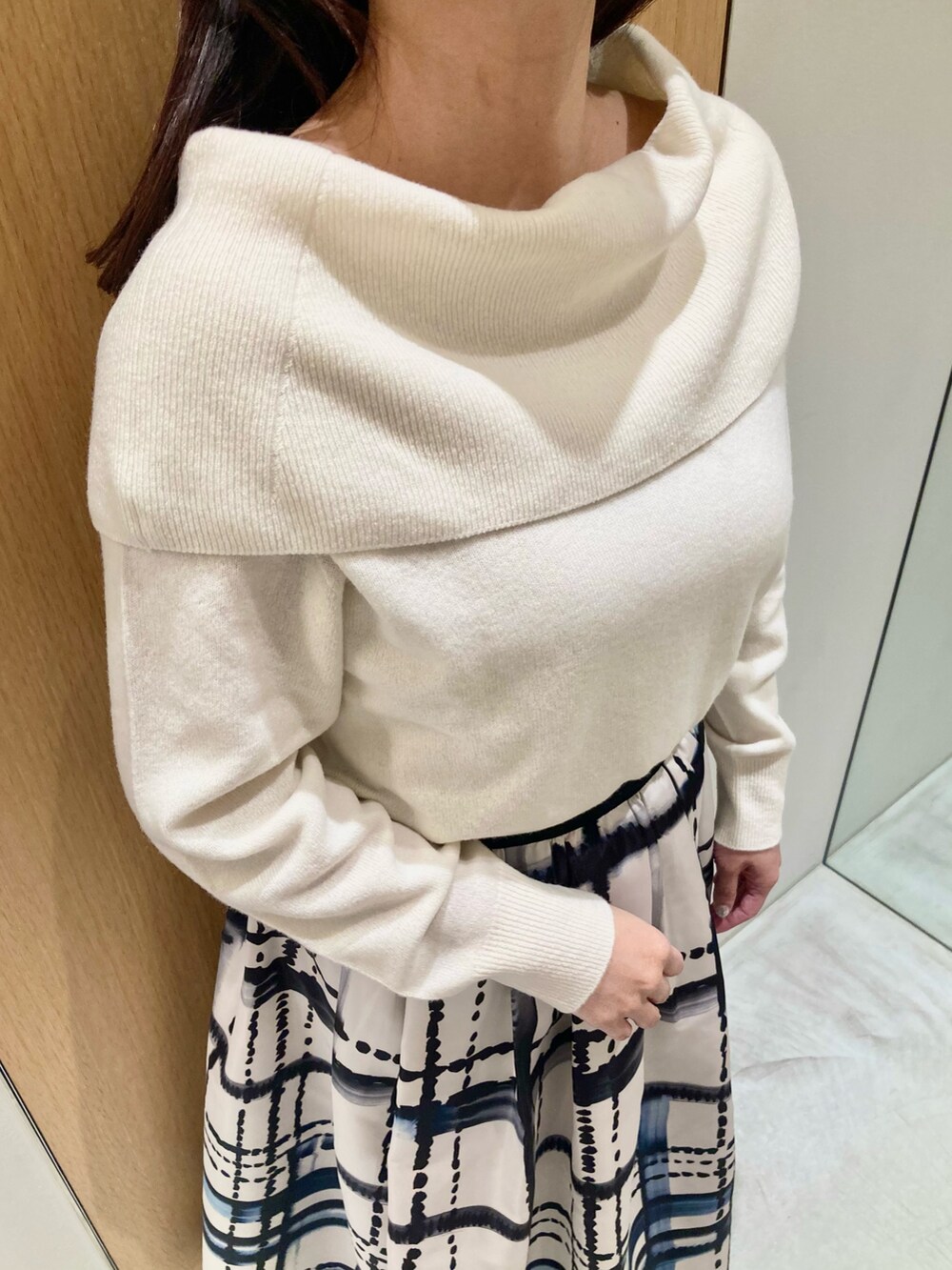 ホワイト系のニット/セーター、ホワイト系のスカート、ブラック系のイヤリングを着用したレディースの秋コーディネートの4枚目の写真