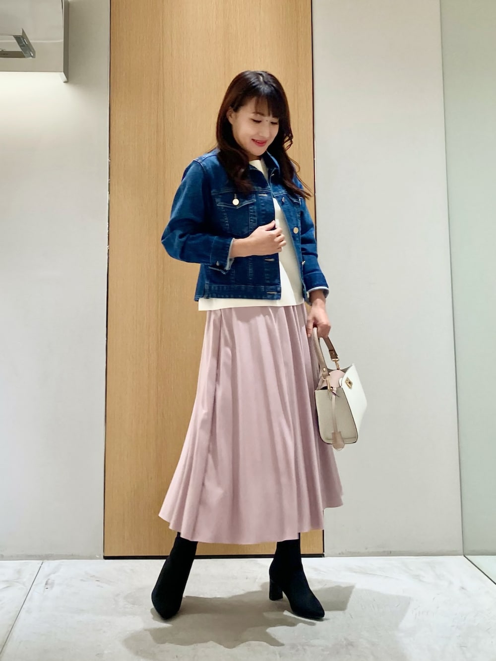 ブルー系のデニムジャケット、ホワイト系のニット/セーター、ピンク系のスカートを着用したレディースの秋コーディネートの2枚目の写真