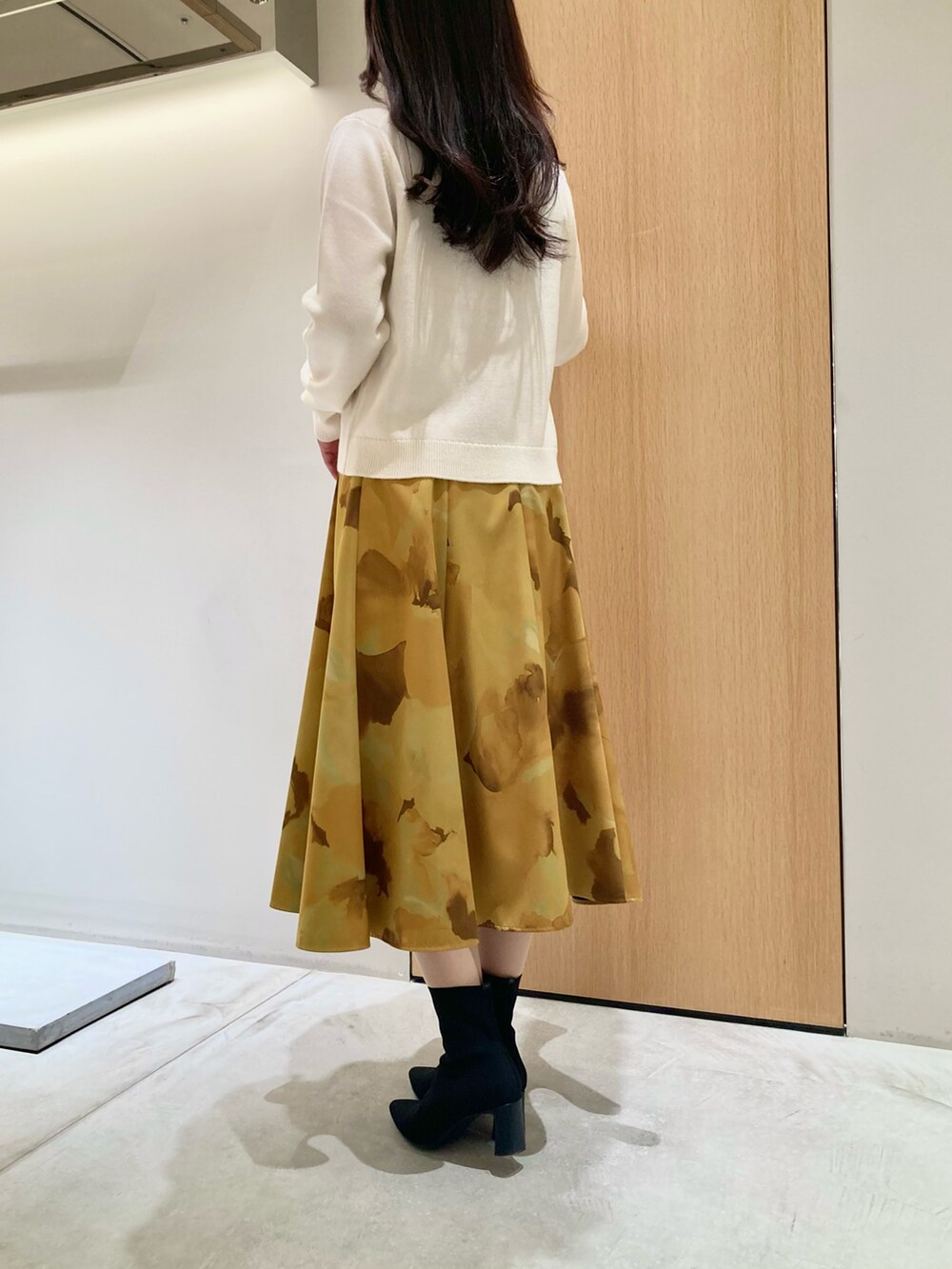 ホワイト系のカーディガン/ボレロ、イエロー系のスカートを着用したレディースの秋コーディネートの4枚目の写真