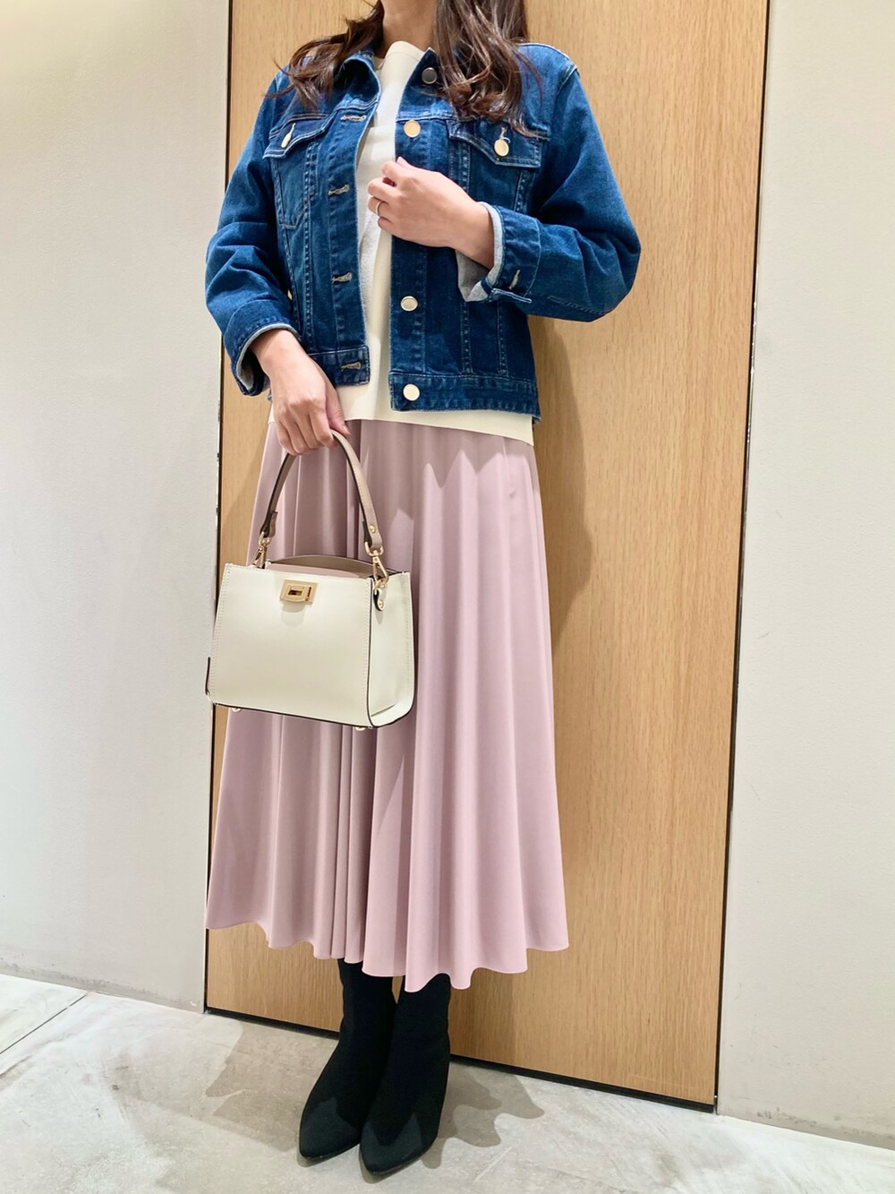 ブルー系のデニムジャケット、ホワイト系のニット/セーター、ピンク系のスカートを着用したレディースの秋コーディネートの5枚目の写真