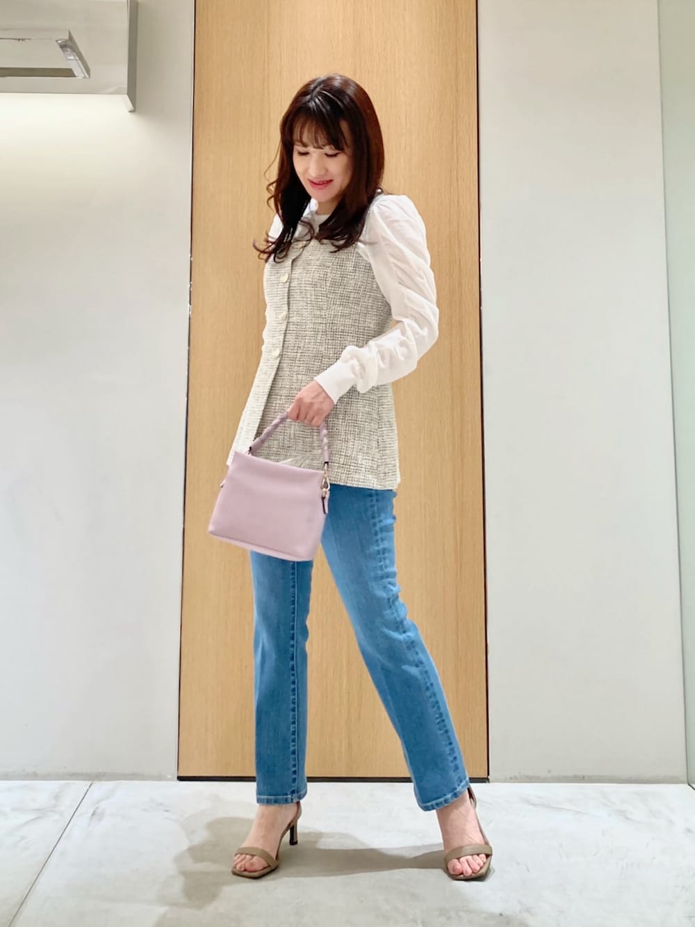 ホワイト系のニット/セーター、ホワイト系のベスト、ブルー系のデニムパンツを着用したレディースの春コーディネートの2枚目の写真