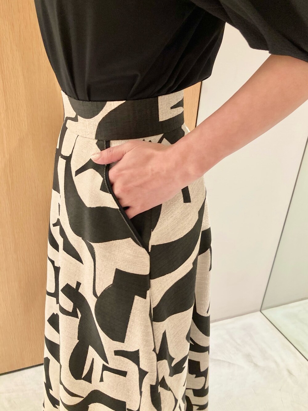 ブラック系のTシャツ/カットソー、ベージュ系のスカート、ブラック系のハンドバッグを着用したレディースの春コーディネートの7枚目の写真