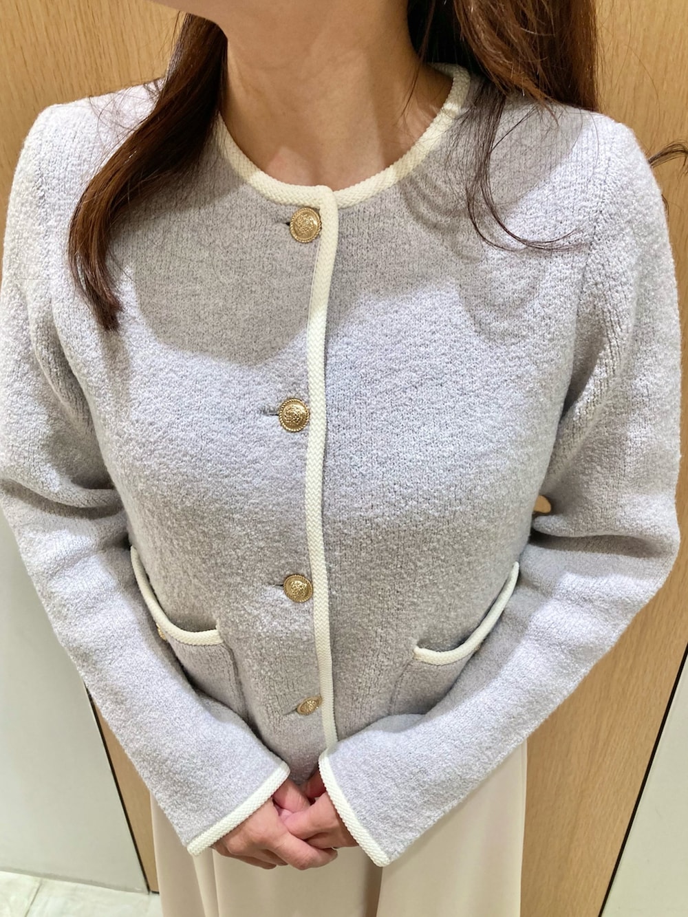 グレー系のカーディガン/ボレロ、ホワイト系のハンドバッグ、ホワイト系のスカートを着用したレディースの秋コーディネートの4枚目の写真