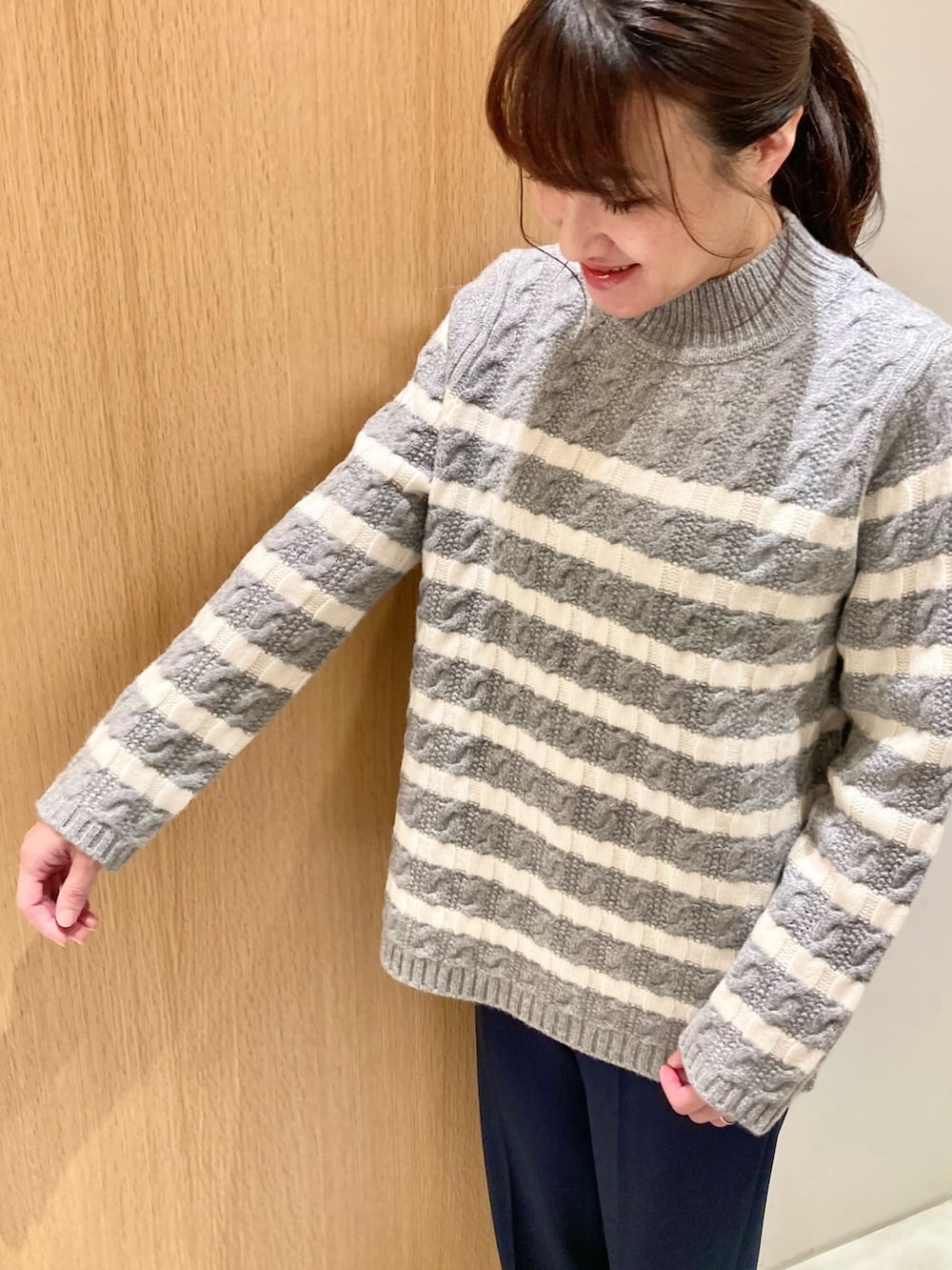 グレー系のニット/セーター、ブルー系のその他パンツ、ホワイト系のハンドバッグを着用したレディースの冬コーディネートの3枚目の写真