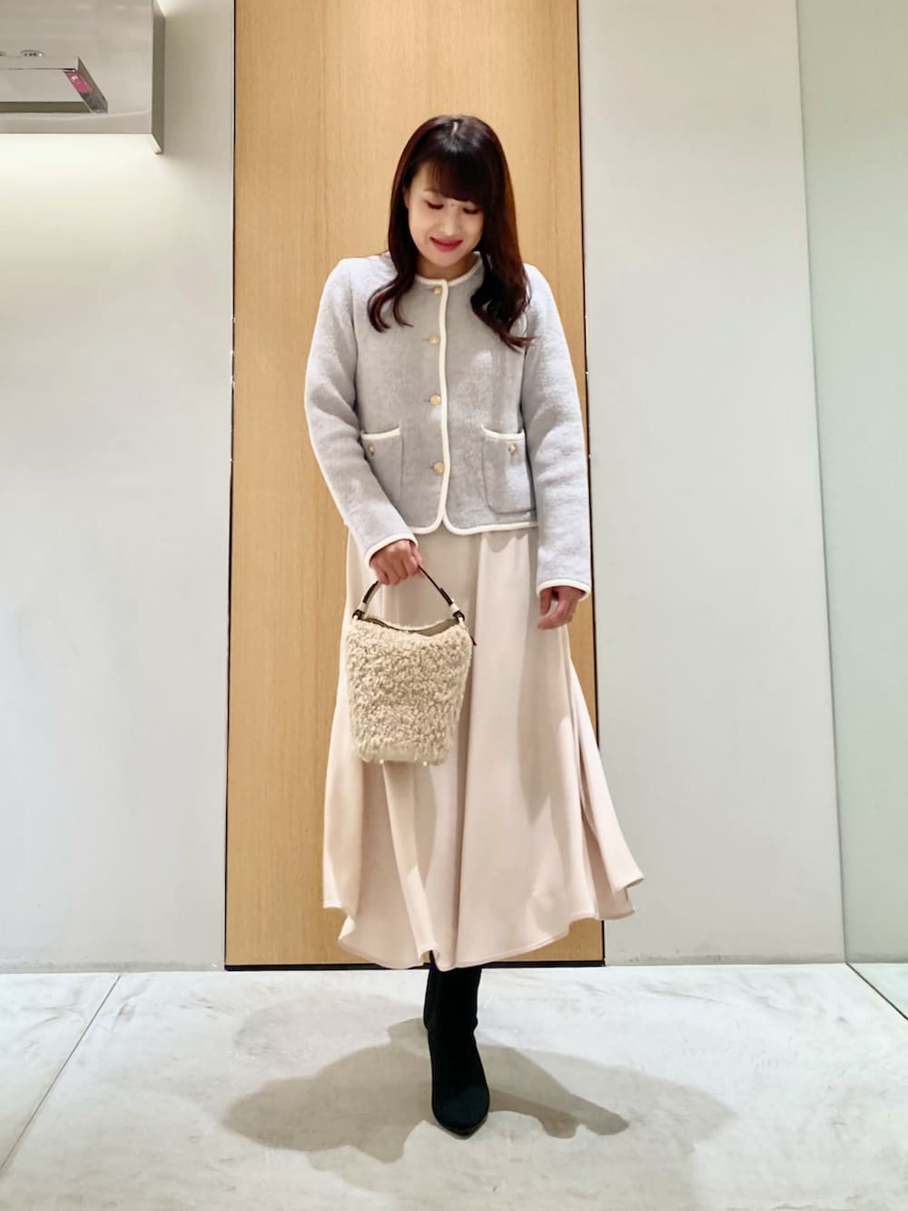 グレー系のカーディガン/ボレロ、ホワイト系のハンドバッグ、ホワイト系のスカートを着用したレディースの秋コーディネートの2枚目の写真