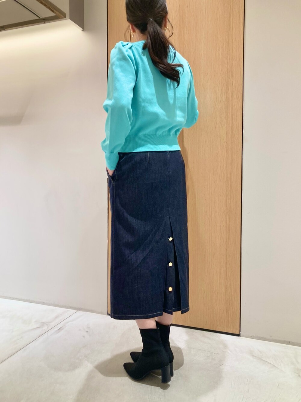 グリーン系のカーディガン/ボレロ、ホワイト系のハンドバッグ、ブルー系のデニムスカートを着用したレディースの冬コーディネートの6枚目の写真