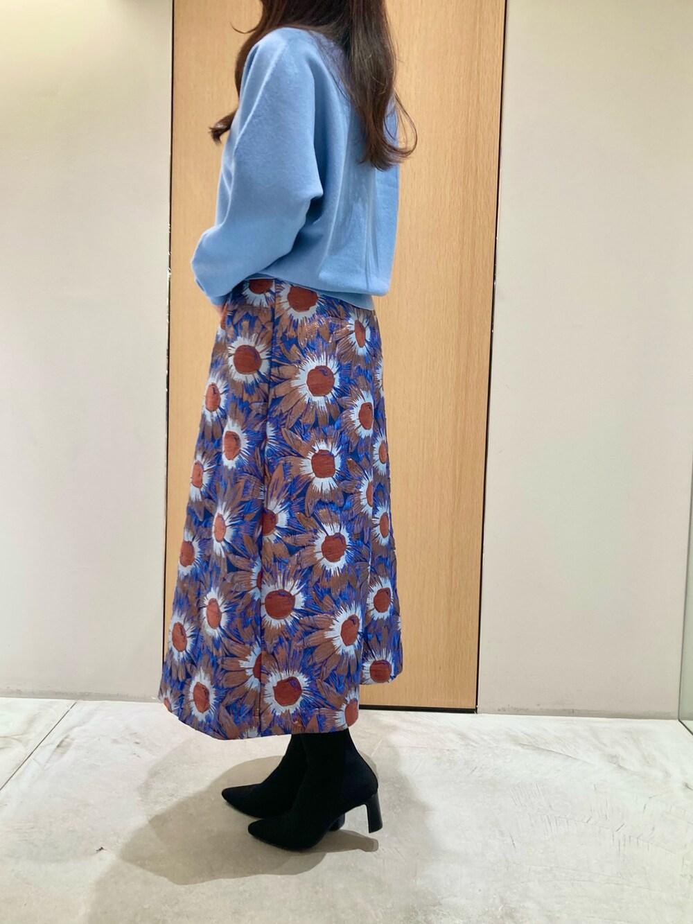 ブルー系のニット/セーター、ブルー系のハンドバッグ、ブルー系のスカートを着用したレディースの秋コーディネートの3枚目の写真