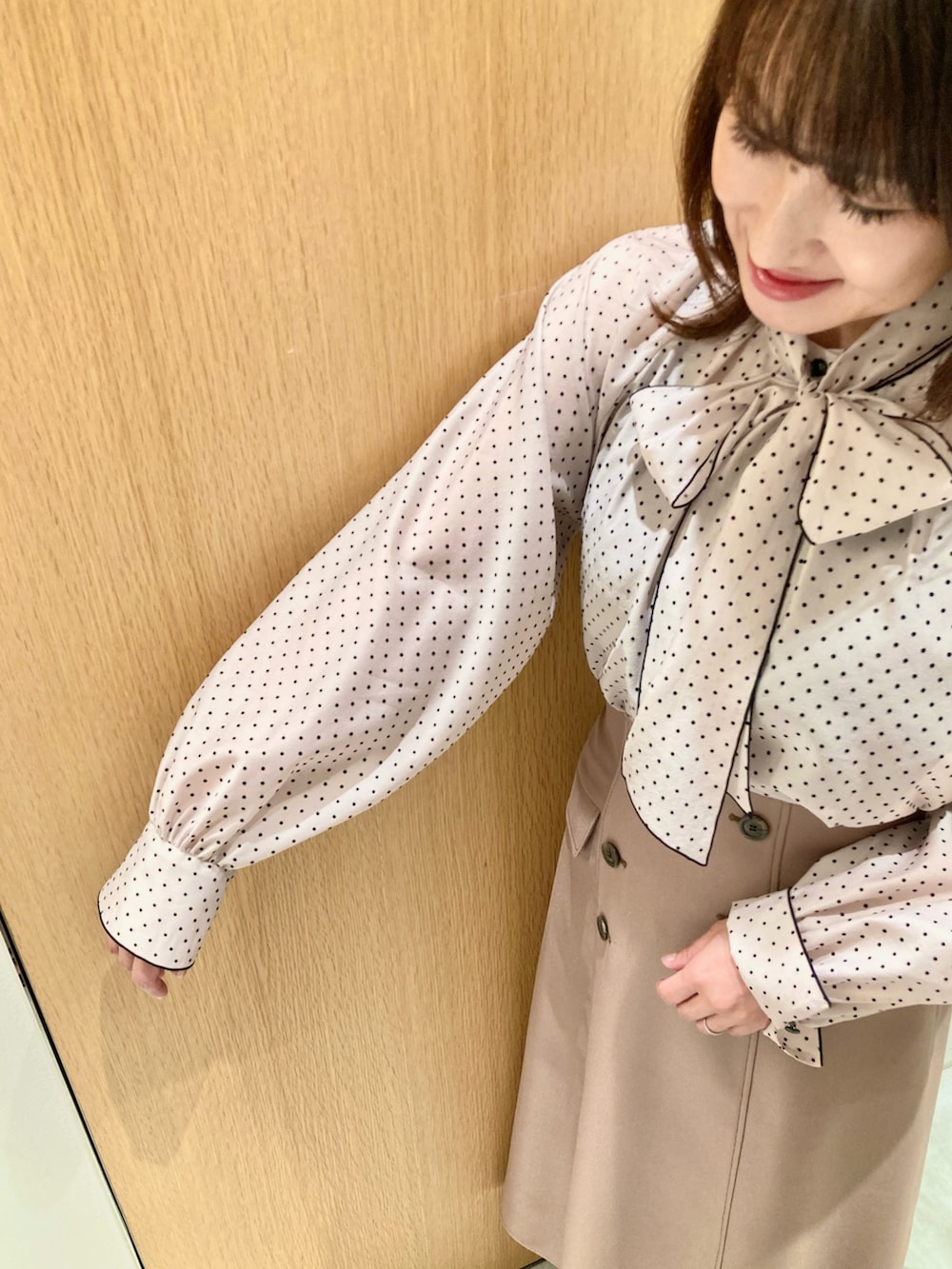 ベージュ系のシャツ/ブラウス、ベージュ系のスカート、ベージュ系のハンドバッグを着用したレディースの秋コーディネートの6枚目の写真