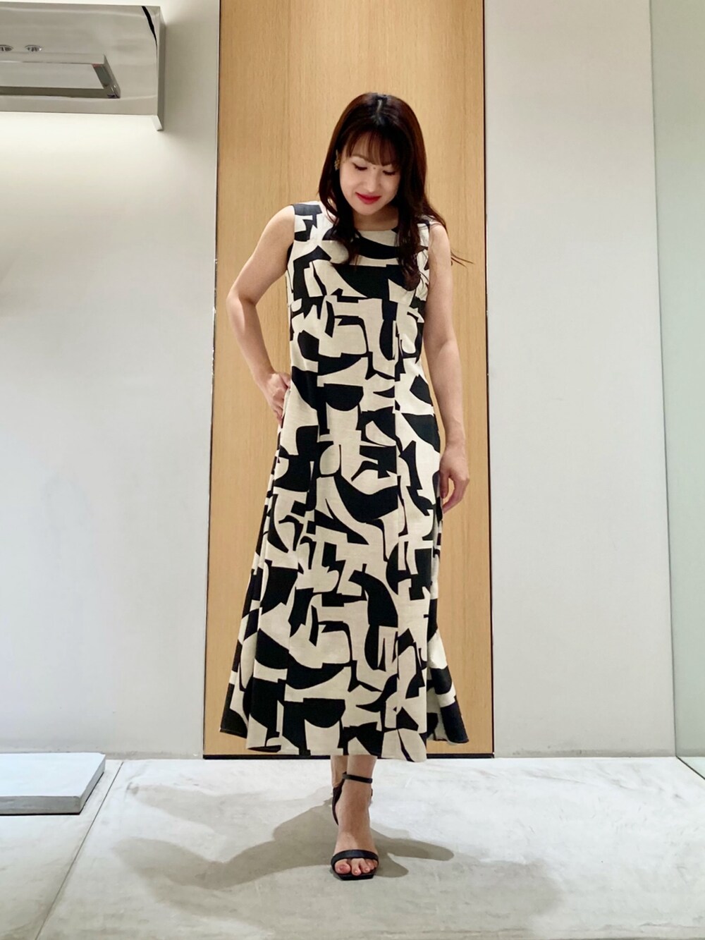 ベージュ系のワンピース、ゴールド系のイヤリングを着用したレディースの夏コーディネートの2枚目の写真