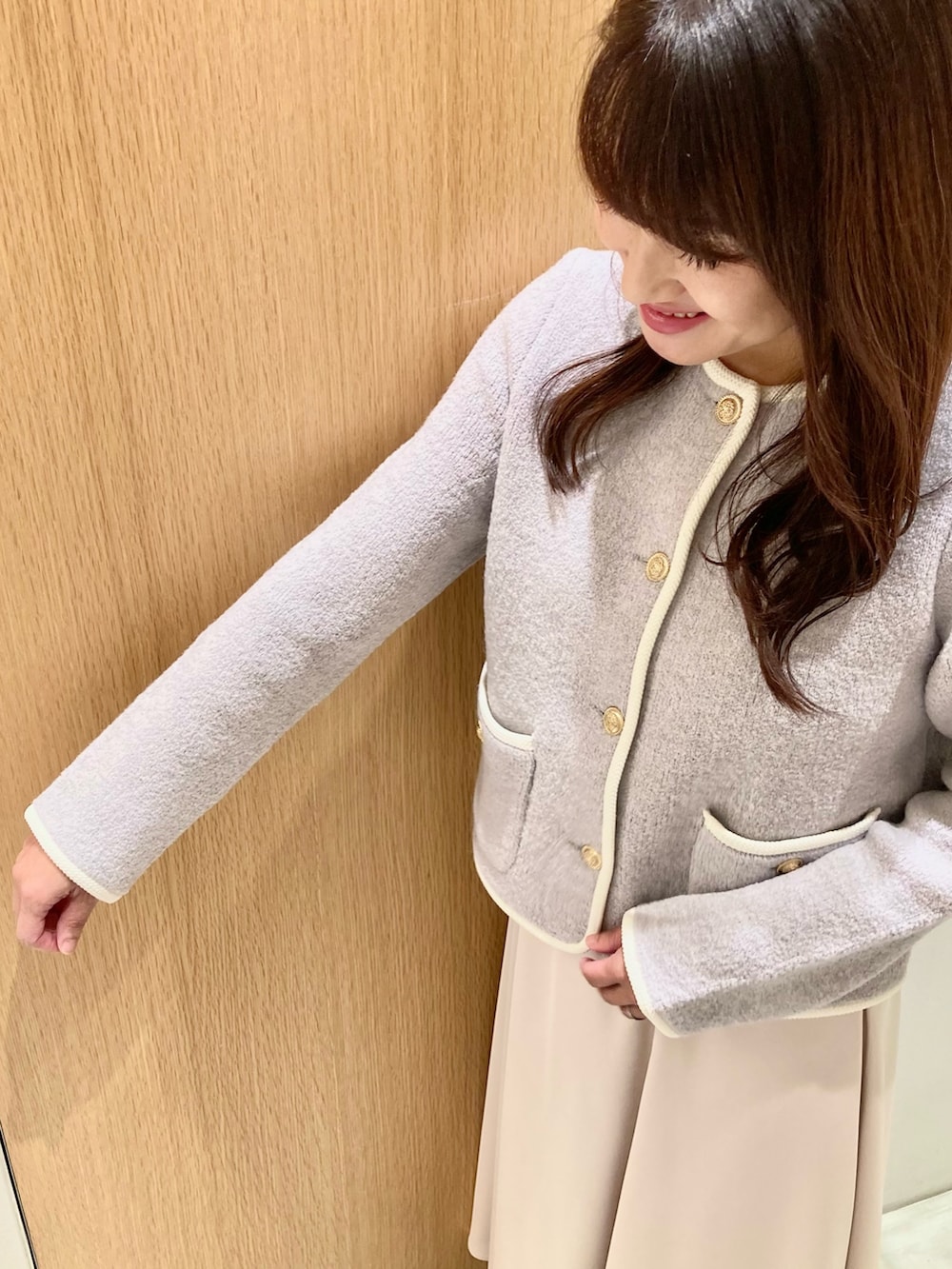 グレー系のカーディガン/ボレロ、ホワイト系のハンドバッグ、ホワイト系のスカートを着用したレディースの秋コーディネートの6枚目の写真