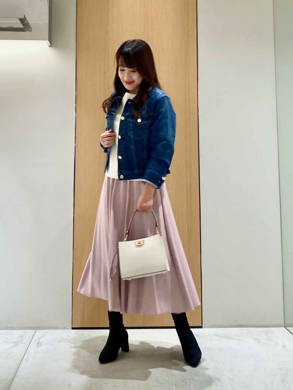ブルー系のデニムジャケット、ホワイト系のニット/セーター、ピンク系のスカートを着用したレディースの秋コーディネートの3枚目の写真
