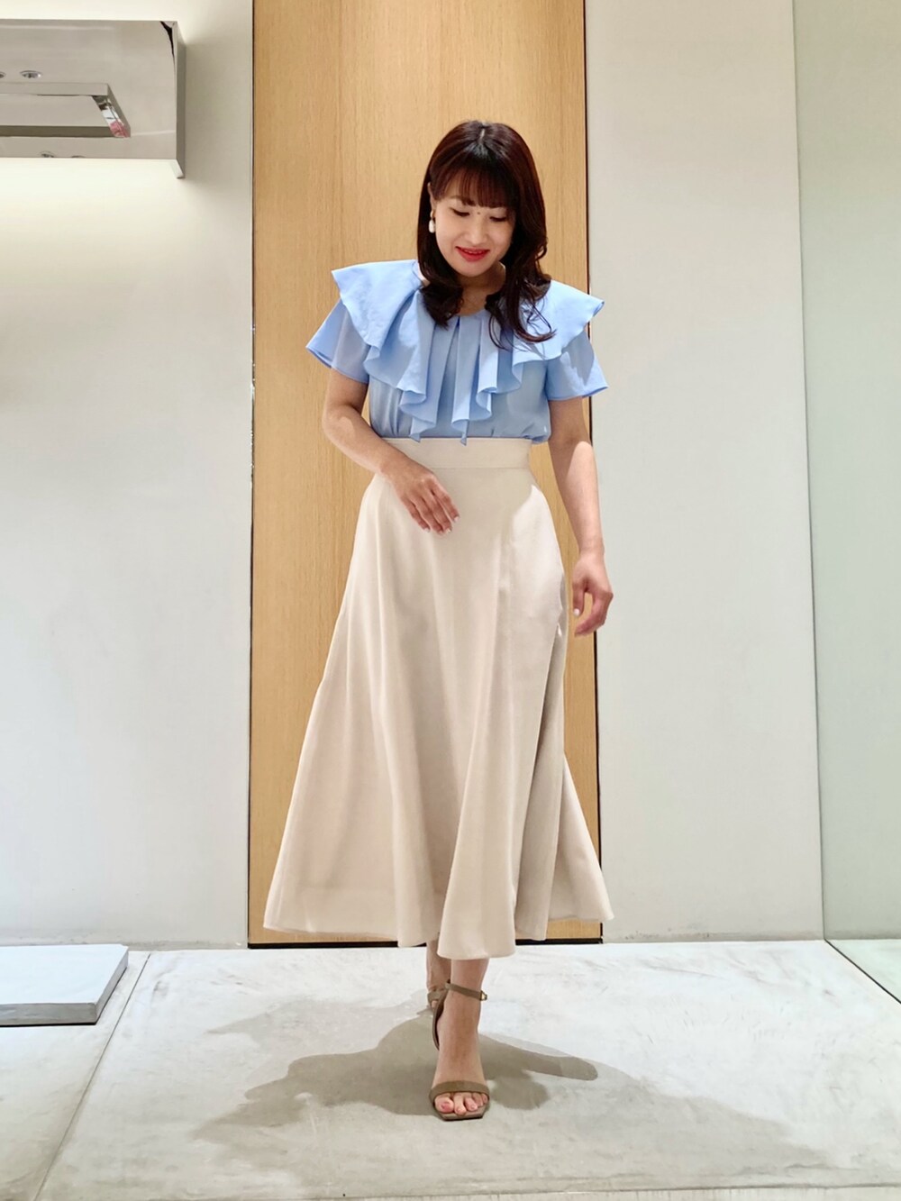 ブルー系のシャツ/ブラウス、ベージュ系のスカート、ホワイト系のイヤリングを着用したレディースの夏コーディネートの2枚目の写真