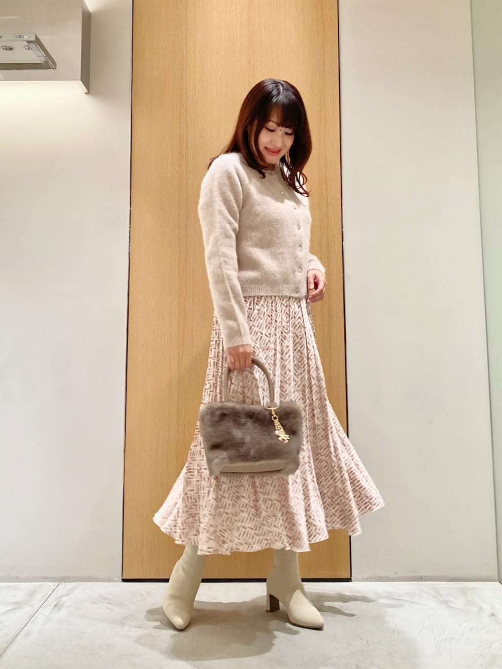 ピンク系のカーディガン/ボレロ、ベージュ系のスカート、ベージュ系のハンドバッグを着用したレディースの秋コーディネートの2枚目の写真