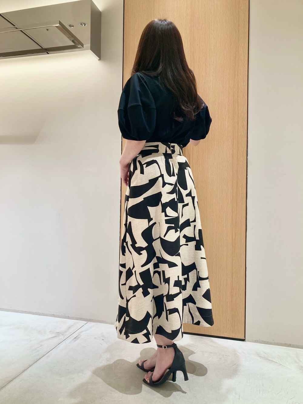 ブラック系のTシャツ/カットソー、ベージュ系のスカート、ブラック系のハンドバッグを着用したレディースの春コーディネートの3枚目の写真