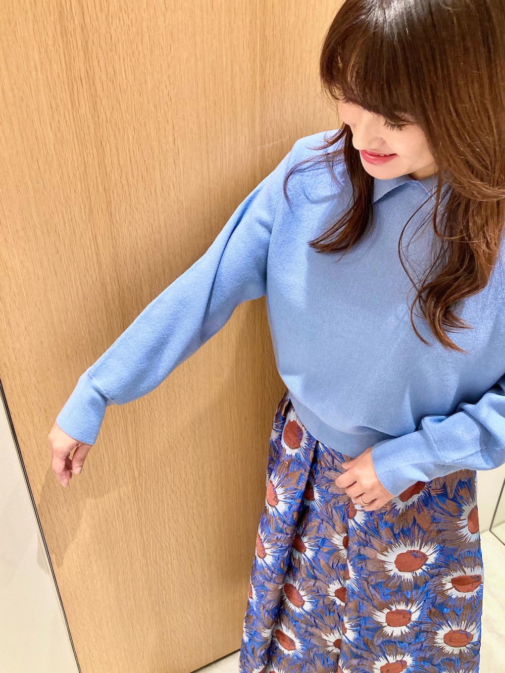 ブルー系のニット/セーター、ブルー系のハンドバッグ、ブルー系のスカートを着用したレディースの秋コーディネートの6枚目の写真