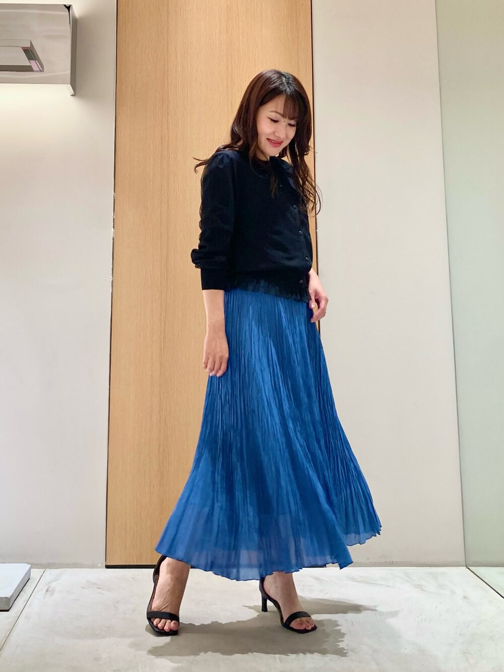 ブラック系のカーディガン/ボレロ、ブルー系のスカート、ホワイト系のイヤリングを着用したレディースの夏コーディネートの2枚目の写真