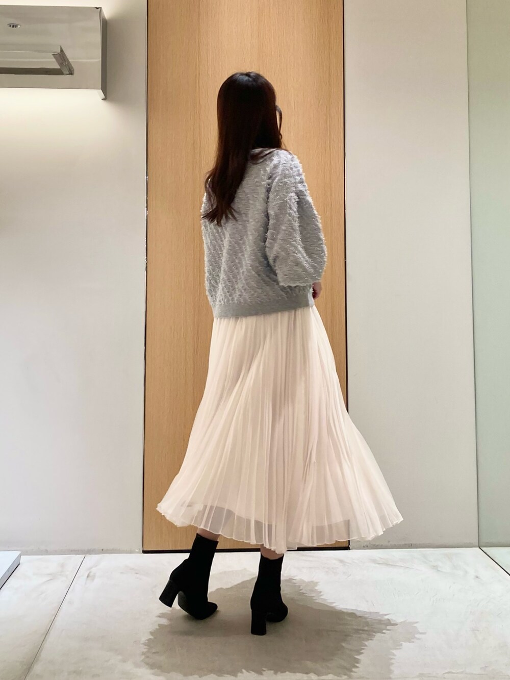 グレー系のニット/セーター、ホワイト系のスカート、シルバー系のネックレスを着用したレディースの秋コーディネートの4枚目の写真