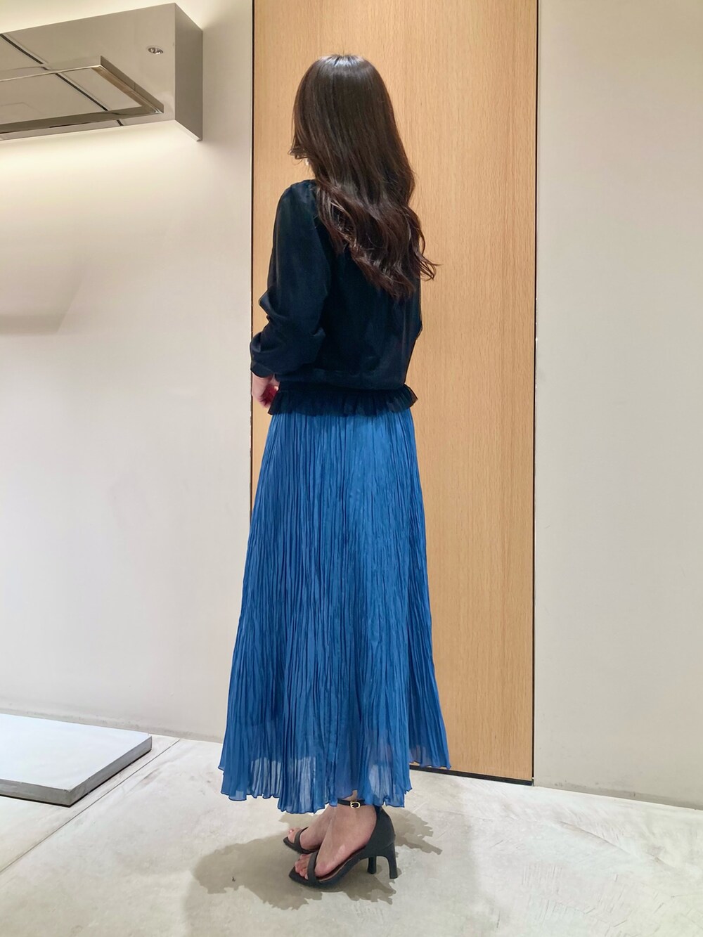 ブラック系のカーディガン/ボレロ、ブルー系のスカート、ホワイト系のイヤリングを着用したレディースの夏コーディネートの3枚目の写真