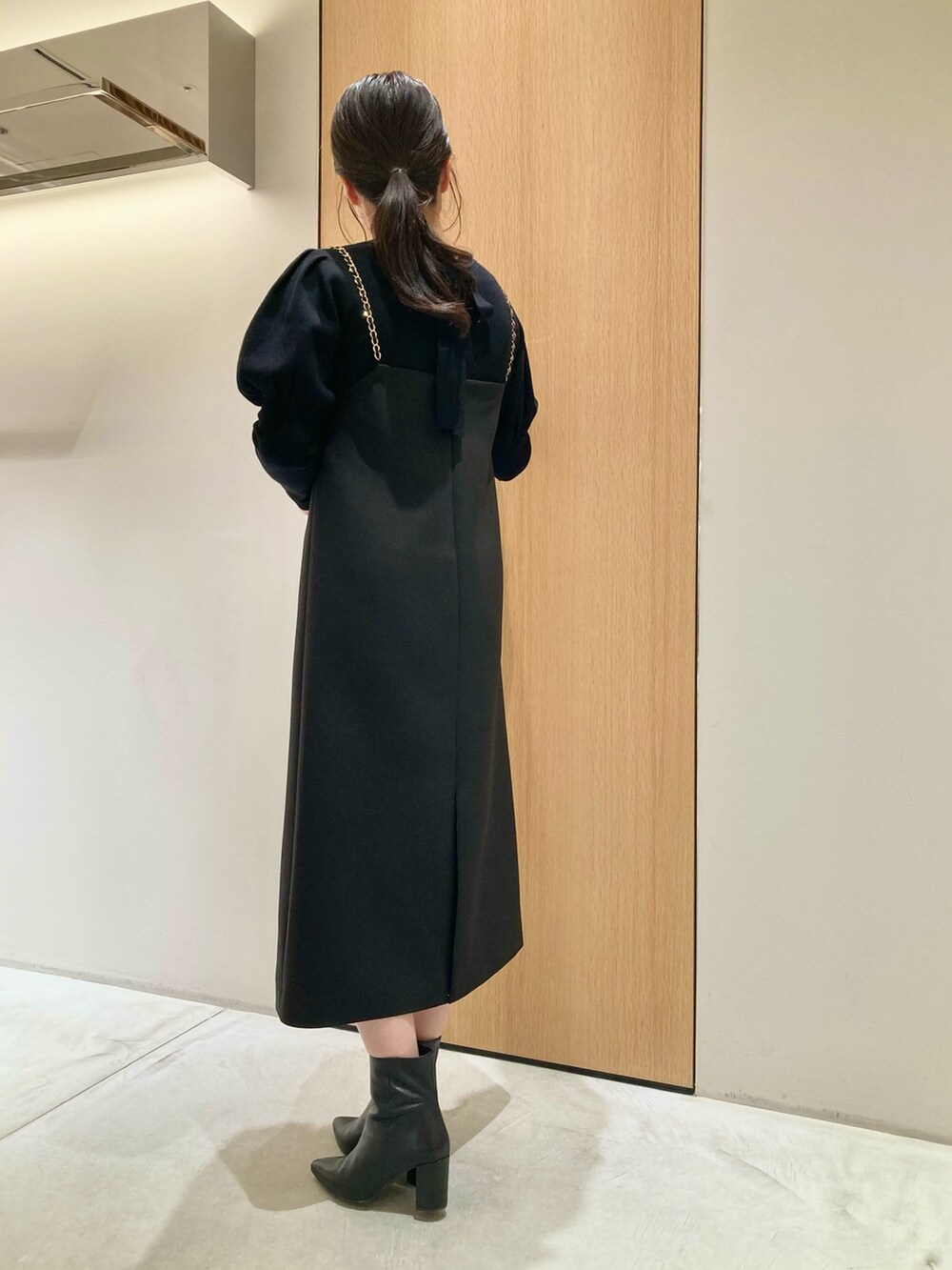 ブラック系のニット/セーター、ブラック系のワンピース、ホワイト系のバックパック/リュックを着用したレディースの秋コーディネートの3枚目の写真