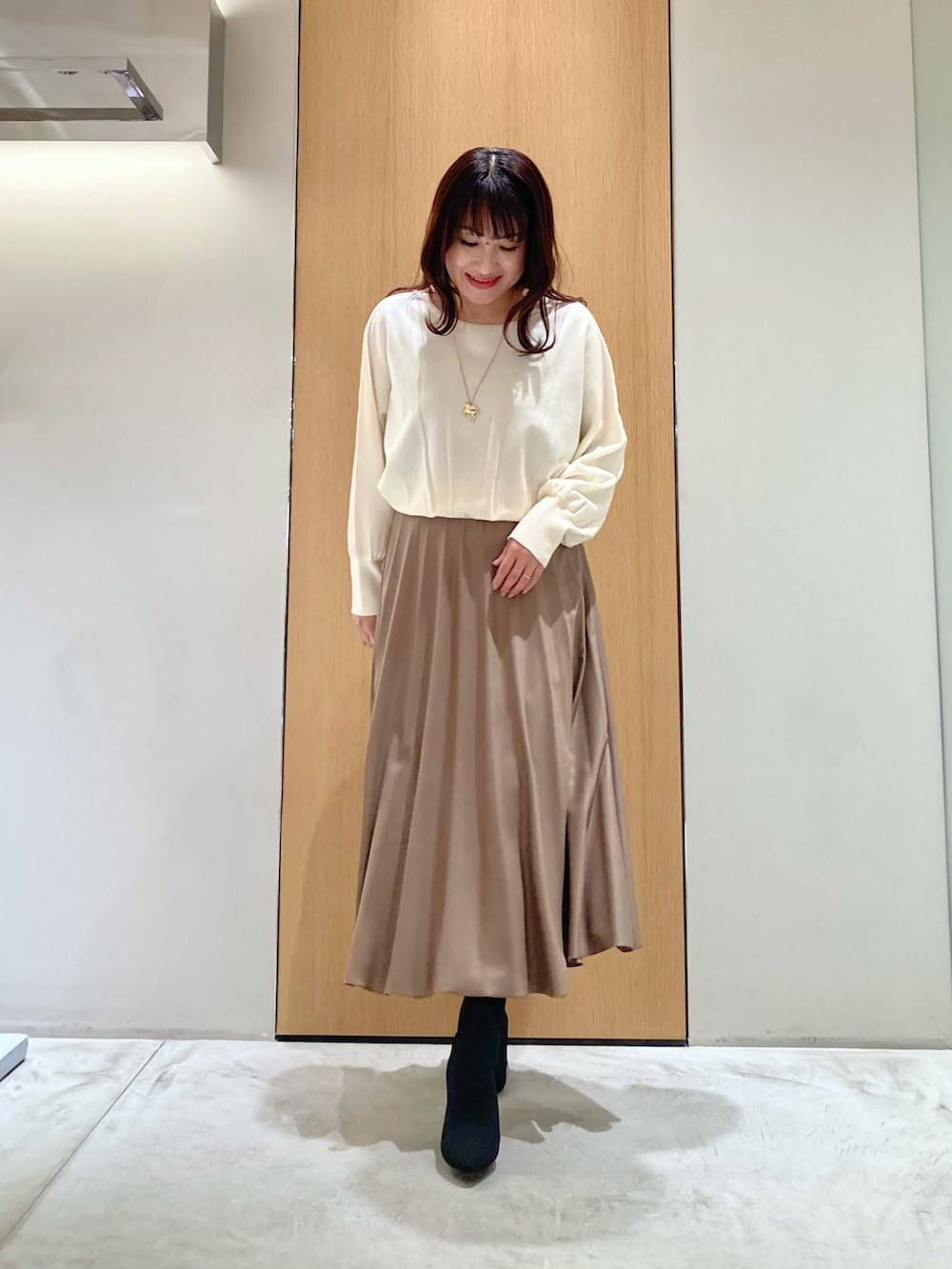 ベージュ系のその他アウター、ホワイト系のニット/セーター、ブラウン系のスカートを着用したレディースの秋コーディネートの4枚目の写真
