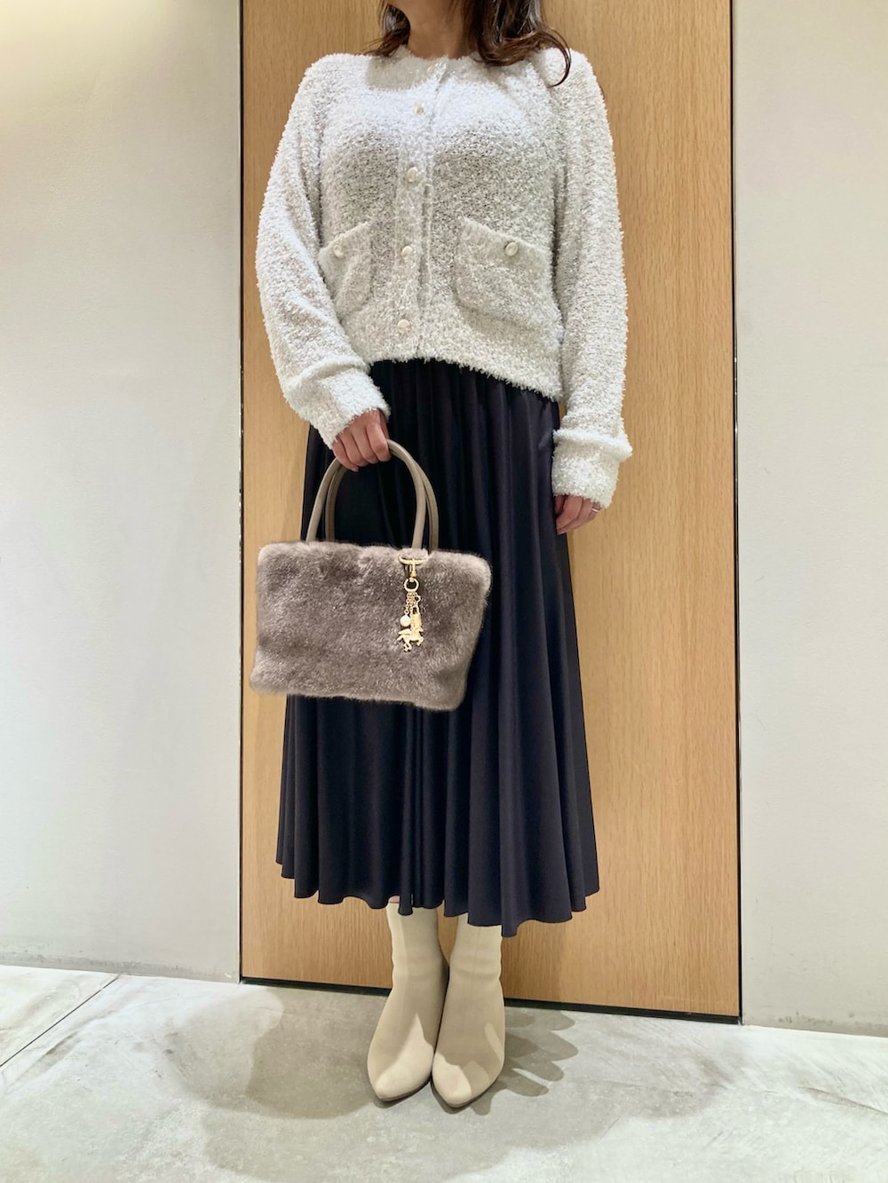 ホワイト系のカーディガン/ボレロ、ベージュ系のハンドバッグ、グレー系のスカートを着用したレディースの秋コーディネートの4枚目の写真